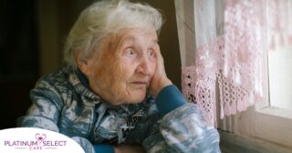 An older woman peacefully looks out of the window while the sun is still up, representing what can happen with sundowning.